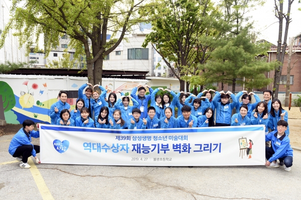 27일 서울 은평구 불광초등학교에서 열린 ‘사랑나눔 벽화 그리기’ 봉사활동에서 삼성생명 청소년 미술대회 역대 수상자 및 관계자들이 기념촬영을 하고 있다.