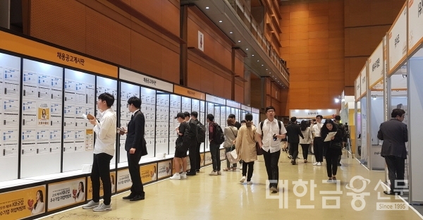 '2019 제1차 KB굿잡 우수기업 취업박람회'에서 채용공고게시판을 확인하고 있는 구직자들.