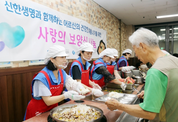 20일 서울 양천어르신종합복지관에서 신한생명 직원봉사자가 어르신에게 보양식 배식을 하고 있다.