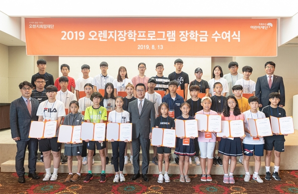 13일 서울 프레지던트호텔에서 열린 ‘2019 오렌지장학프로그램’ 장학금 수여식에서 정문국 이사장(가운데)과 오렌지장학프로그램의 장학생들이 수여식을 가진 후 기념촬영을 하고 있다.