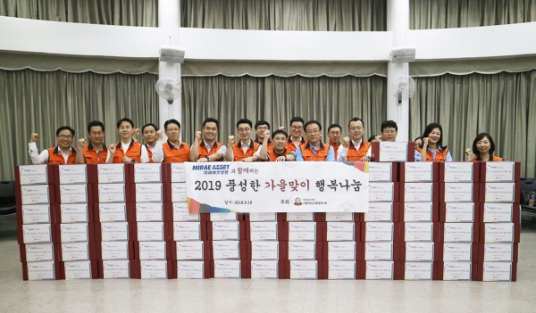19일 서울 마포노인종합복지관에서 미래에셋생명 임직원들이 마포구 저소득층 노인 100여 명에게 전달할 선물세트를 포장하고 기념촬영을 하고 있다.
