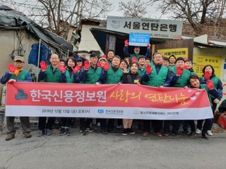 한국신용정보원 임직원들이 13일 서울 노원구 백사마을을 방문해 취약계층을 위한 '연탄 나눔 봉사활동'을 실시하고 기념촬영을 하고 있다.