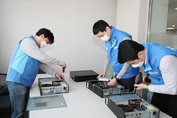 신한생명 직원이 소외아동을 위한 온라인 강의용 PC를 지원하기 위해 컴퓨터 본체의 하드 디스크를 교체하고 있는 모습
