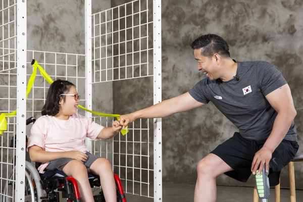 한민수 전 패럴림픽 국가대표 선수가 휠체어 사용 아동의 신체 발달을 위한 재활운동을 돕고 있다.(사진: 상상인그룹)